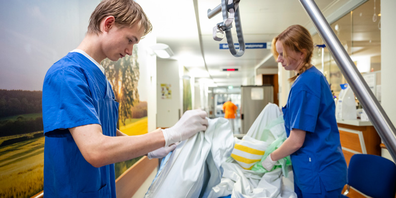 Ein Junge und ein Mädchen des FSJ beziehen gemeinsam ein Patientenbett